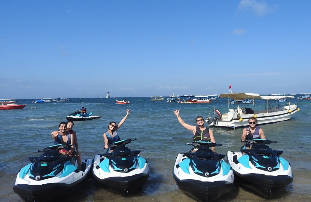 Tourists engaging in water sports like jet skiing and paddleboarding at Nusa Dua Beach